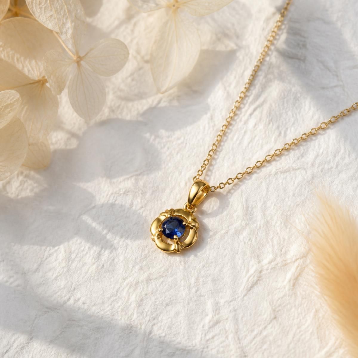 Gold pendant necklace set with a blue sapphire